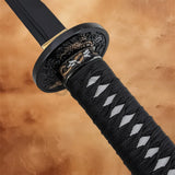 Detailed view of the black wrapped katana handle with a decorative black and gold guard.