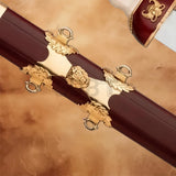 Close-up of the Gladiator Antique Sword Replica scabbard featuring ornate gold-tone fittings, decorative lion emblem, and rich burgundy finish.